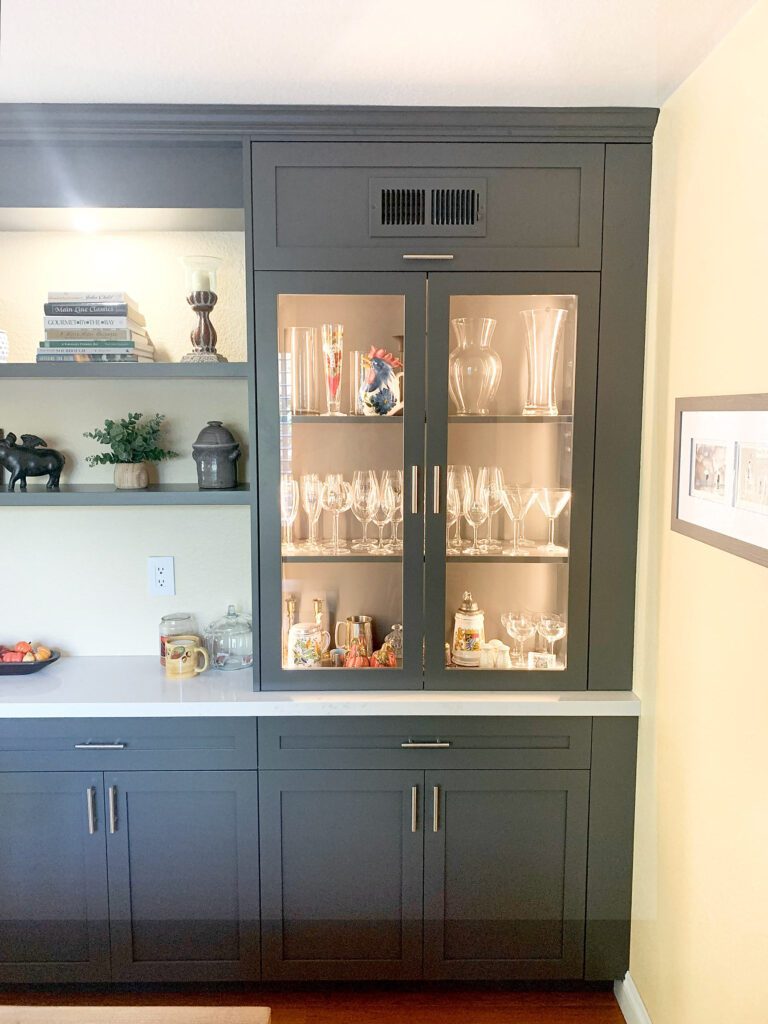 Built-in storage with dark bluish-gray wood cabinet doors and framing, topped with glass-door showcase units. Detail