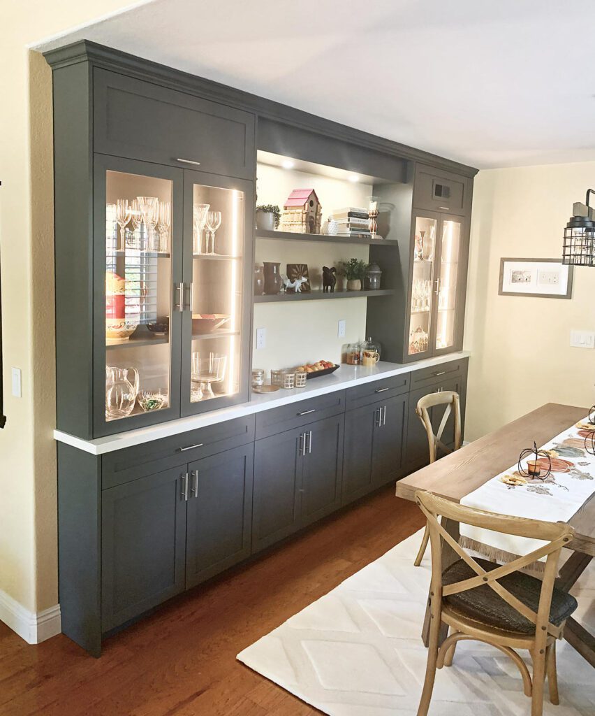 Built-in storage with dark bluish-gray wood cabinet doors and framing, topped with glass-door showcase units.