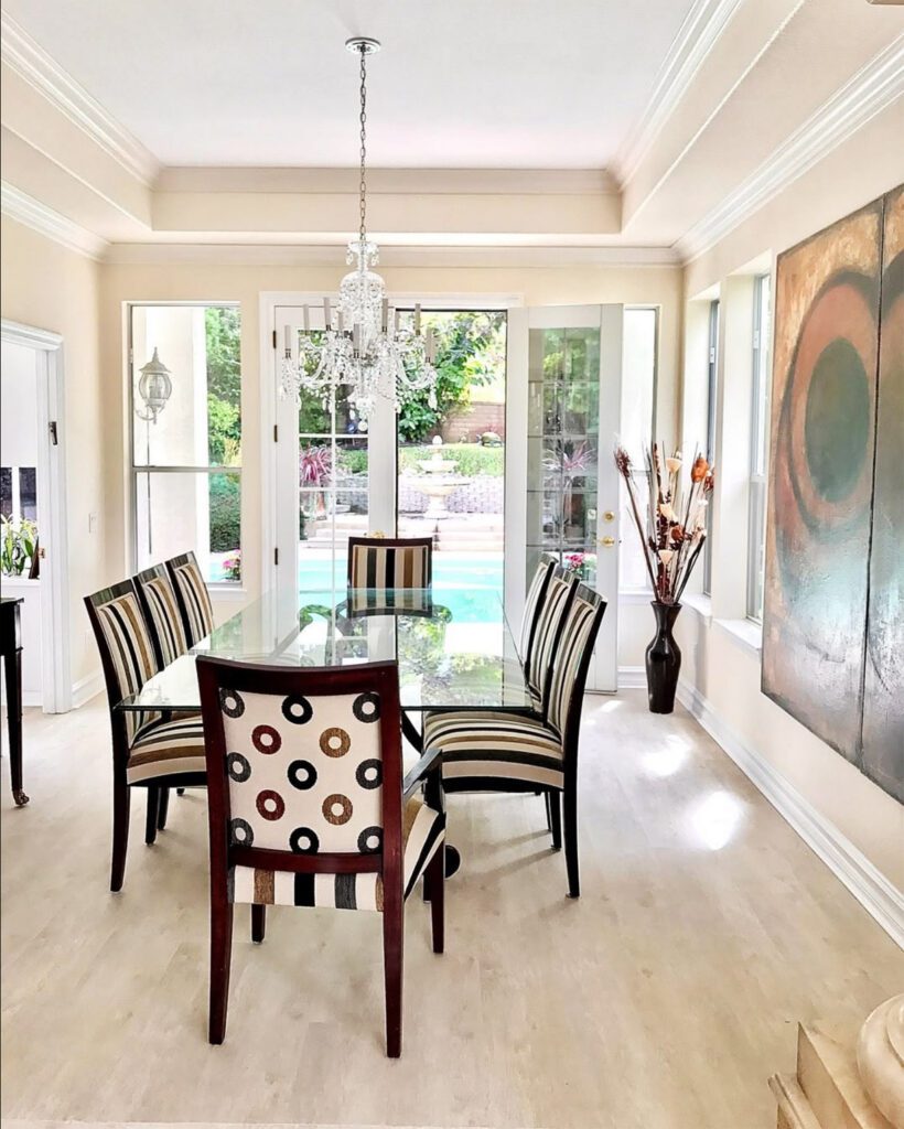 living room remodeling: a table in the middle and big painting on a wall, big glass door behind